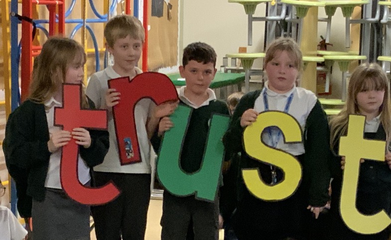 Children holding letters spelling 'Trust'